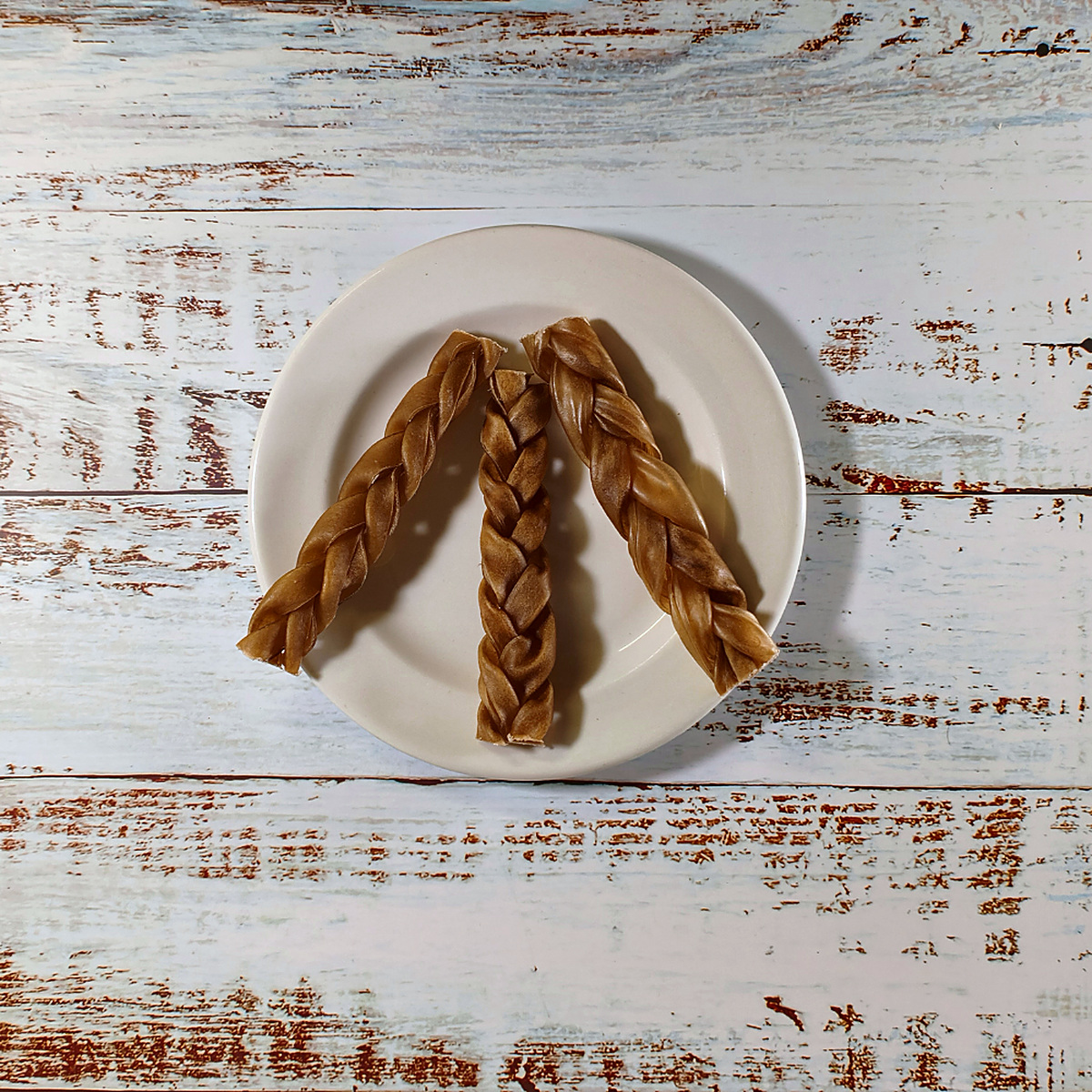 Three braided goat chews for dogs on a plate