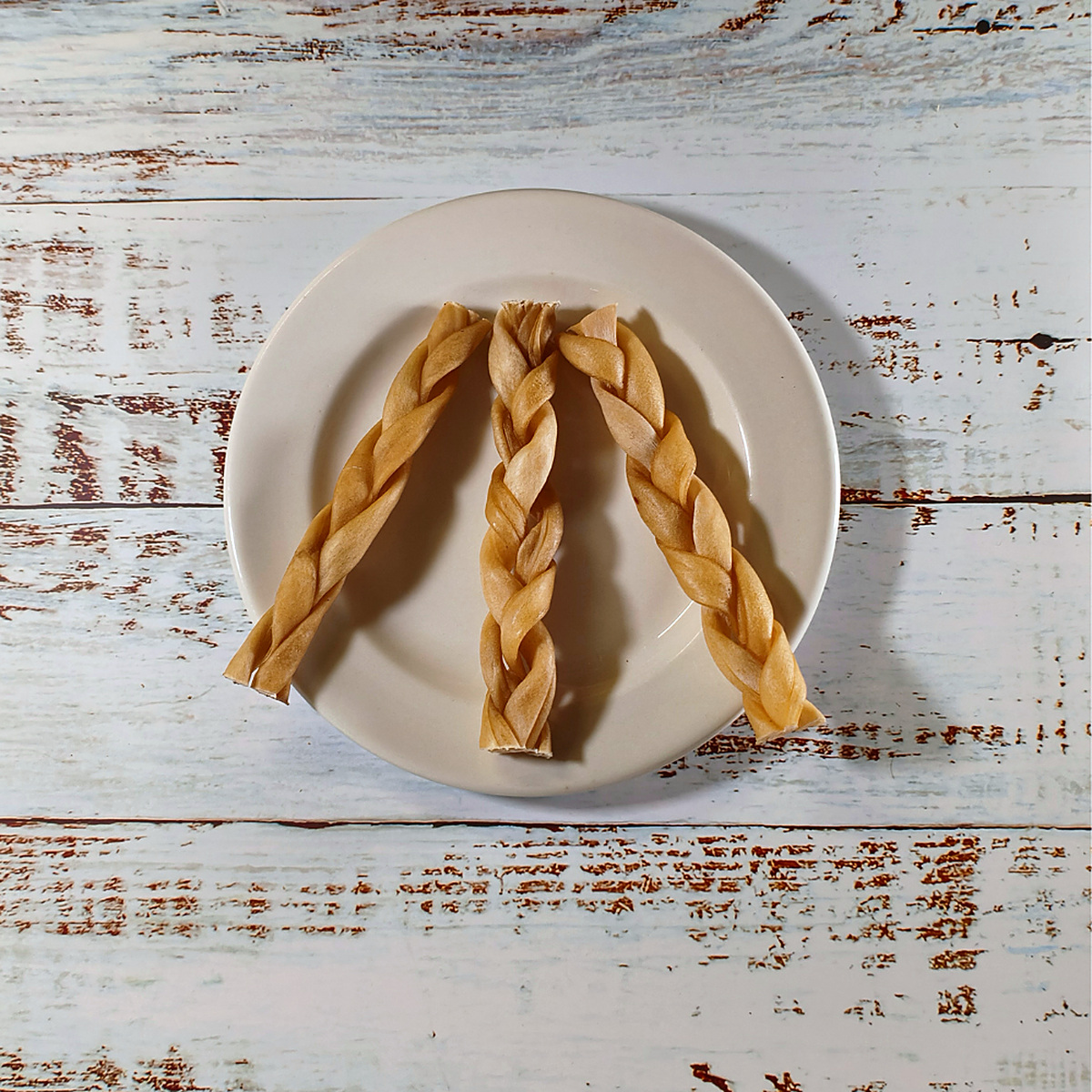 Three braided lamb chews for dogs on a plate