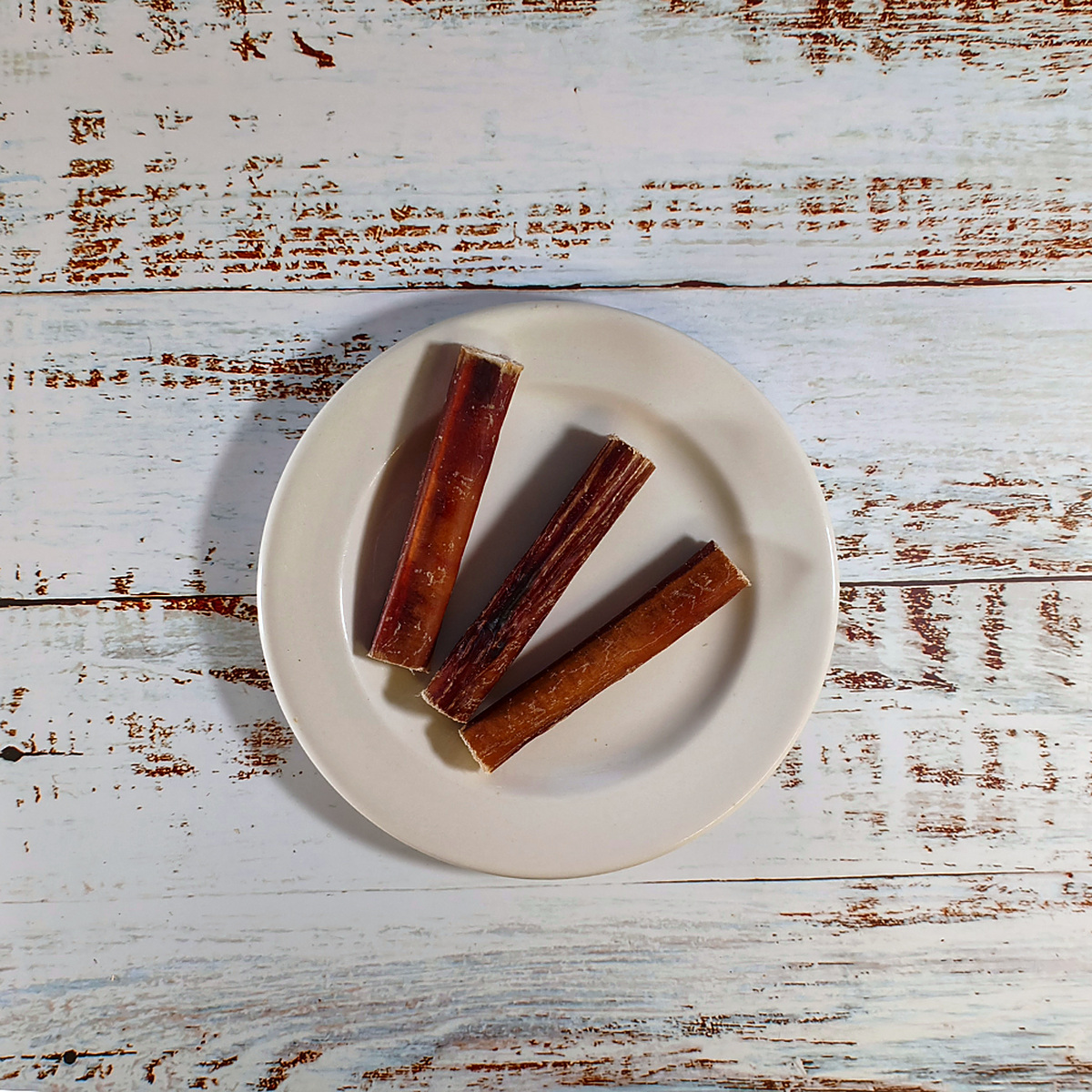 Three bully pizzle sticks for dogs on a plate