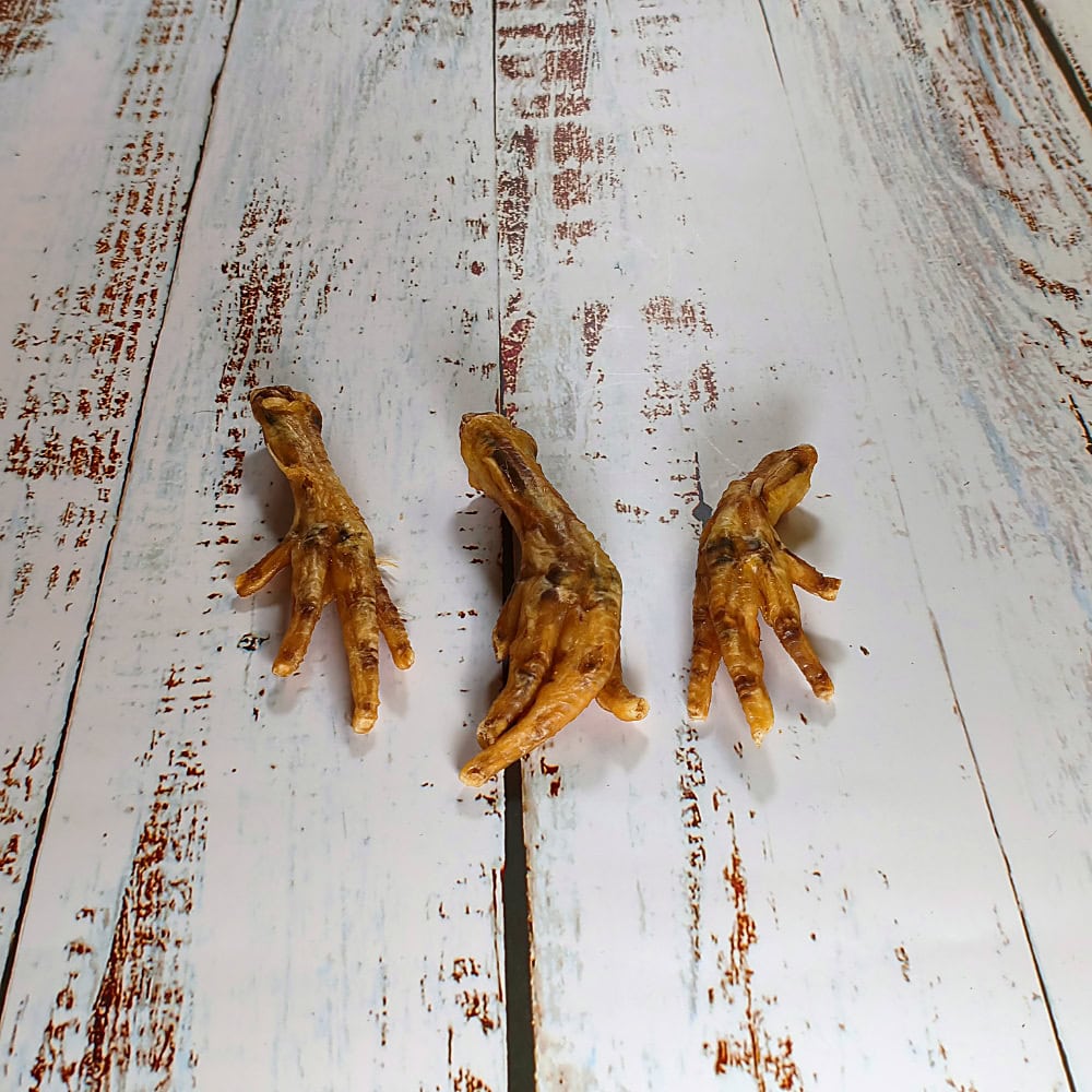 Three natural chicken feet dog treats laid side by side showing their natural variation in size