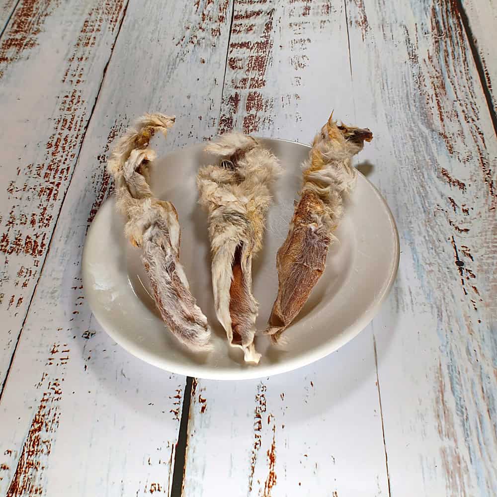 Three natural hairy rabbit ears on a cream plate showing their fur and natural variation