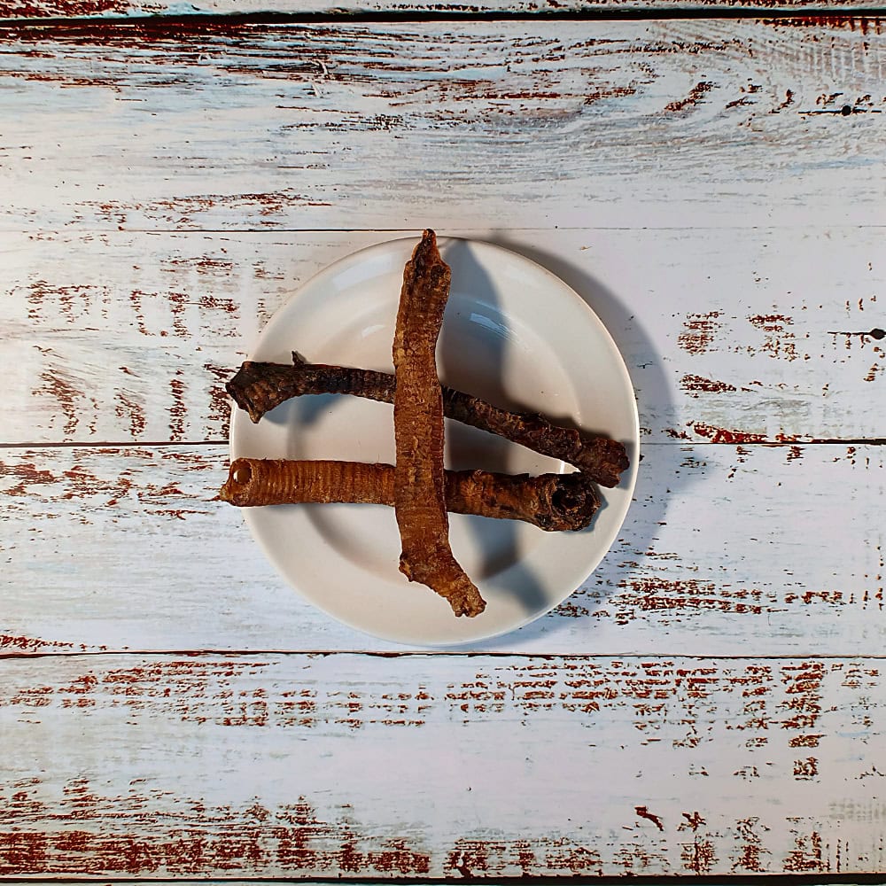 Three Lamb Tubes natural dog chews on a cream plate on a whitewashed wooden board