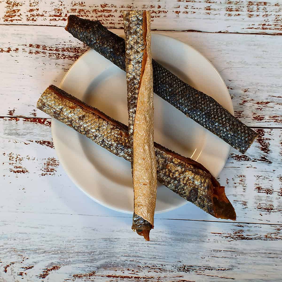 Three salmon skin rolls for dogs on a plate