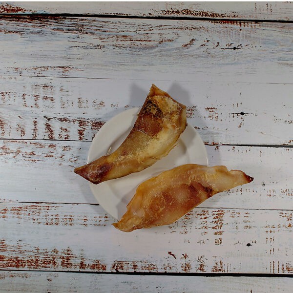 Two moon bones natural dog chews on a cream plate on a whitewashed wooden board