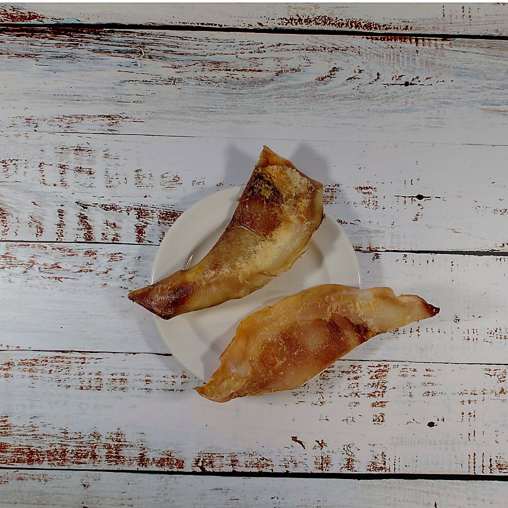 Two moon bones natural dog chews on a cream plate on a whitewashed wooden board