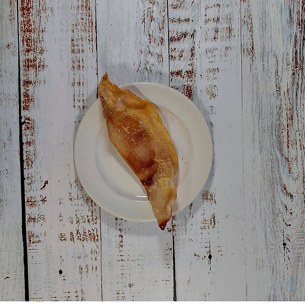 A single moon bone dog chew on a cream plate, showing its natural size and shape