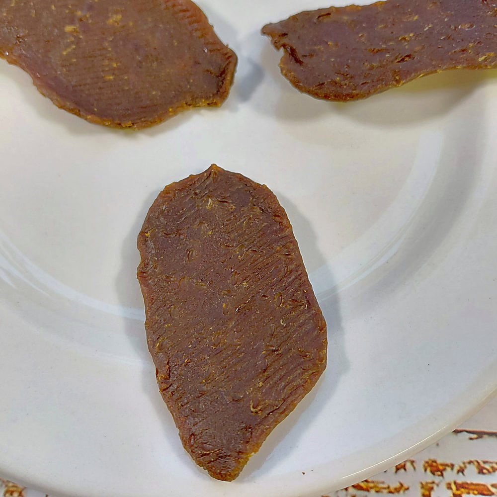 A close view of smoked ostrich dog treats showing the ridged texture and natural grain